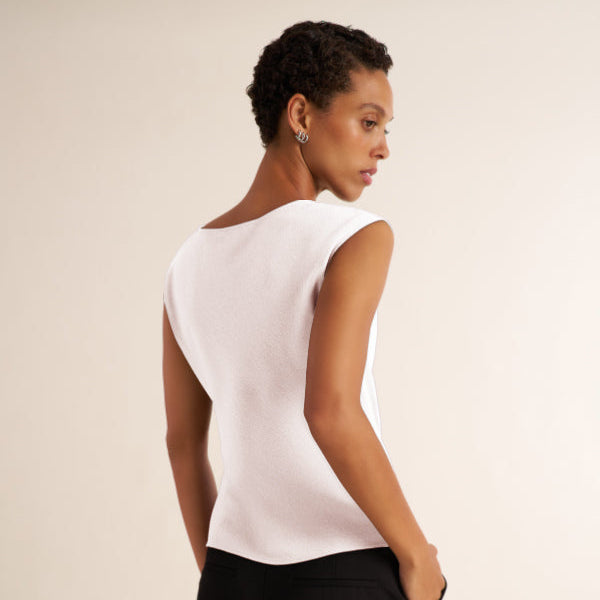 Woman wearing a white, draped cap sleeve shirt with black pants
