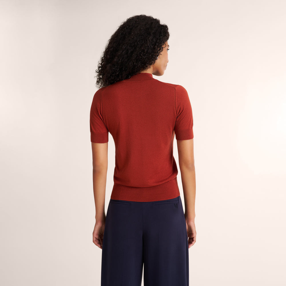 Woman wearing an orange spice color short sleeve sweater with navy wide leg pants