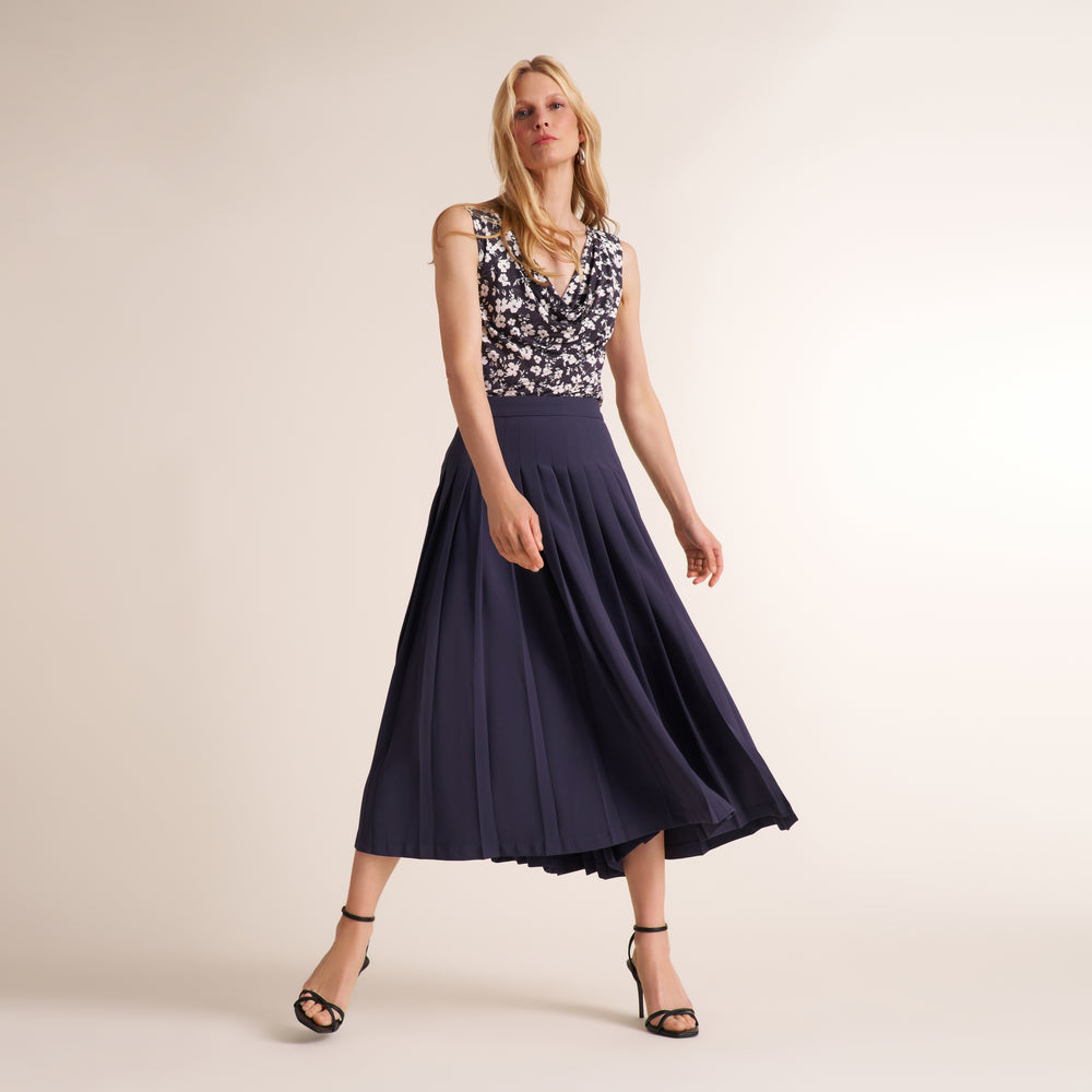 Woman wearing a a printed black and white top with a navy gray long skirt