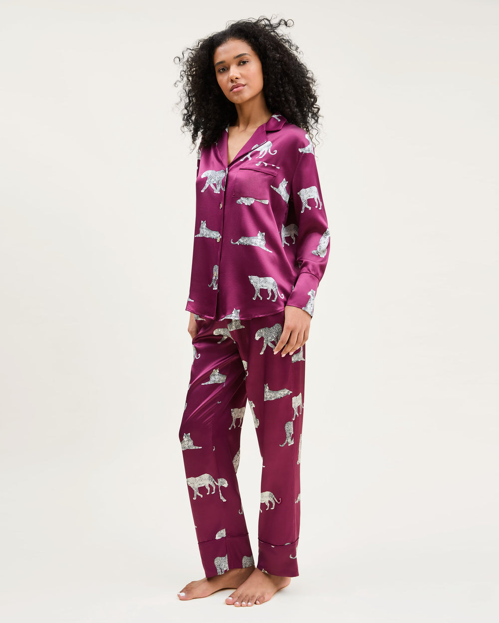 Woman wearing a purple pajama set with animal prints on a white background