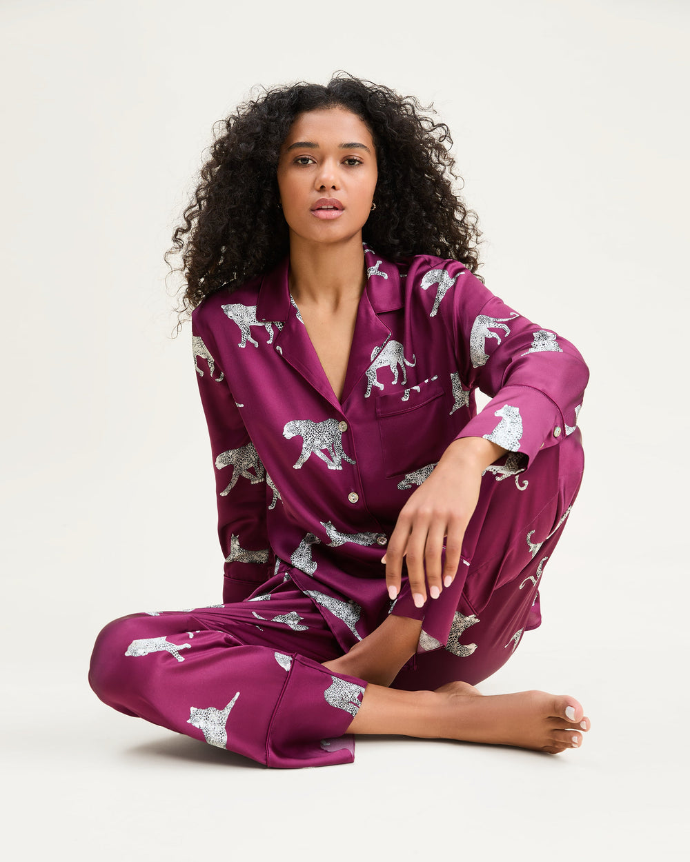Woman wearing a purple pajama set with animal prints on a white background