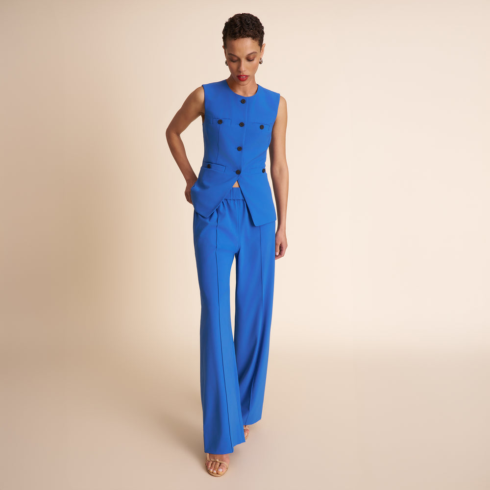 Woman wearing a blue jumpsuit with a beige background