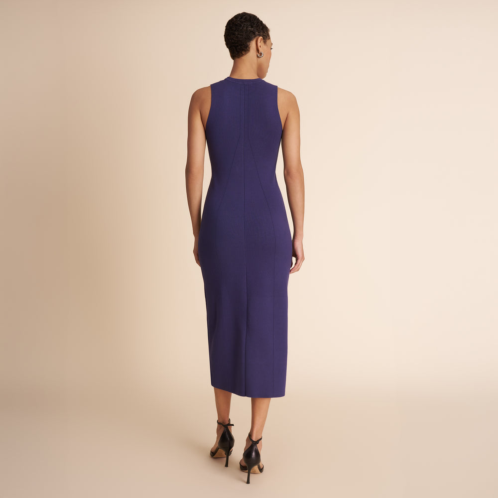 Woman wearing a sleeveless purple dress against a beige background