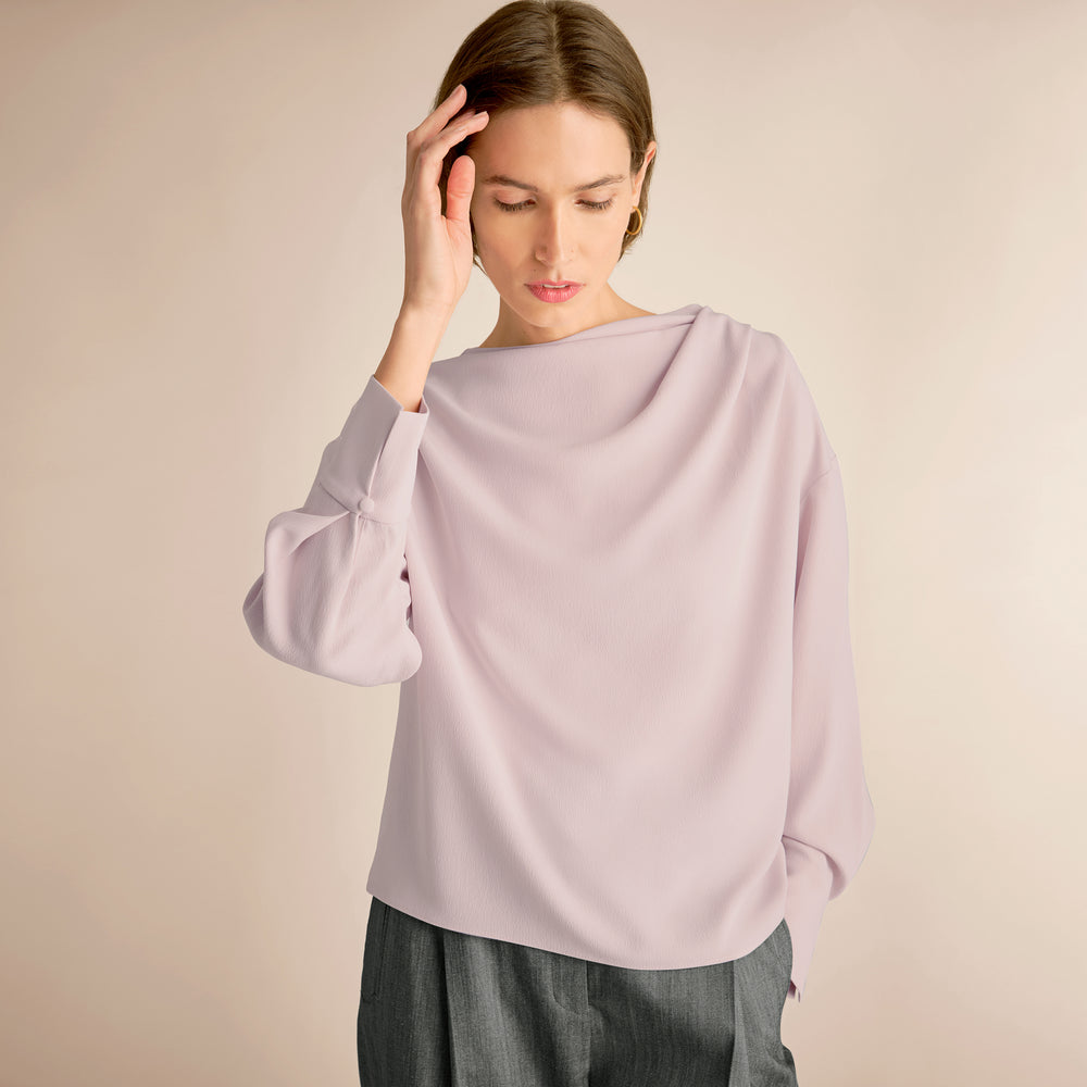 Woman wearing a light purple blouse against a beige background