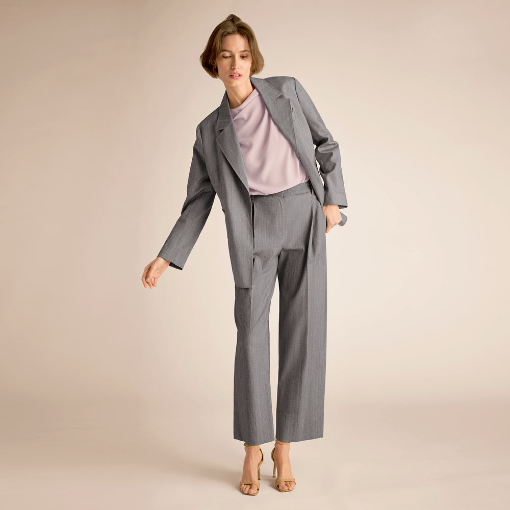 Woman wearing a gray suit with a light pink top on a beige background