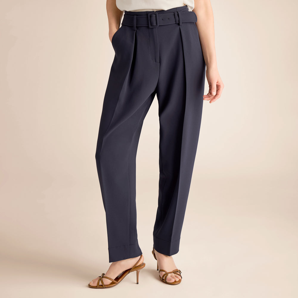 Navy blue pants worn by a person on a beige background