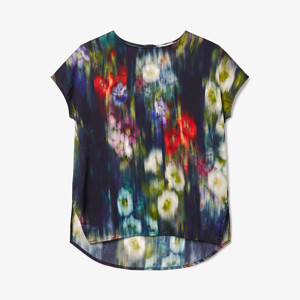 A short-sleeve high-low top featuring an abstract painterly floral print with red, white, blue, and purple flowers on a dark background, displayed flat against a light gray background.