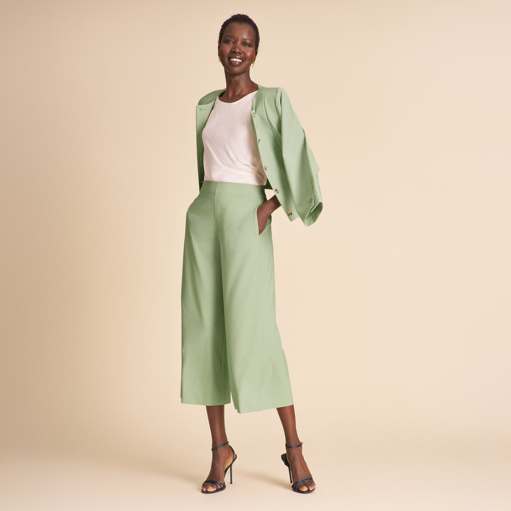 Woman wearing a green outfit with a beige background