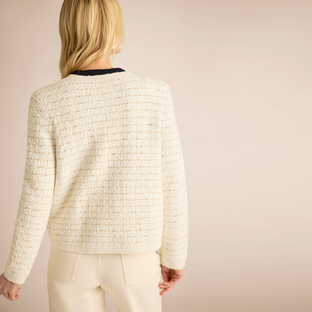 Person wearing a textured white jacket on a plain background