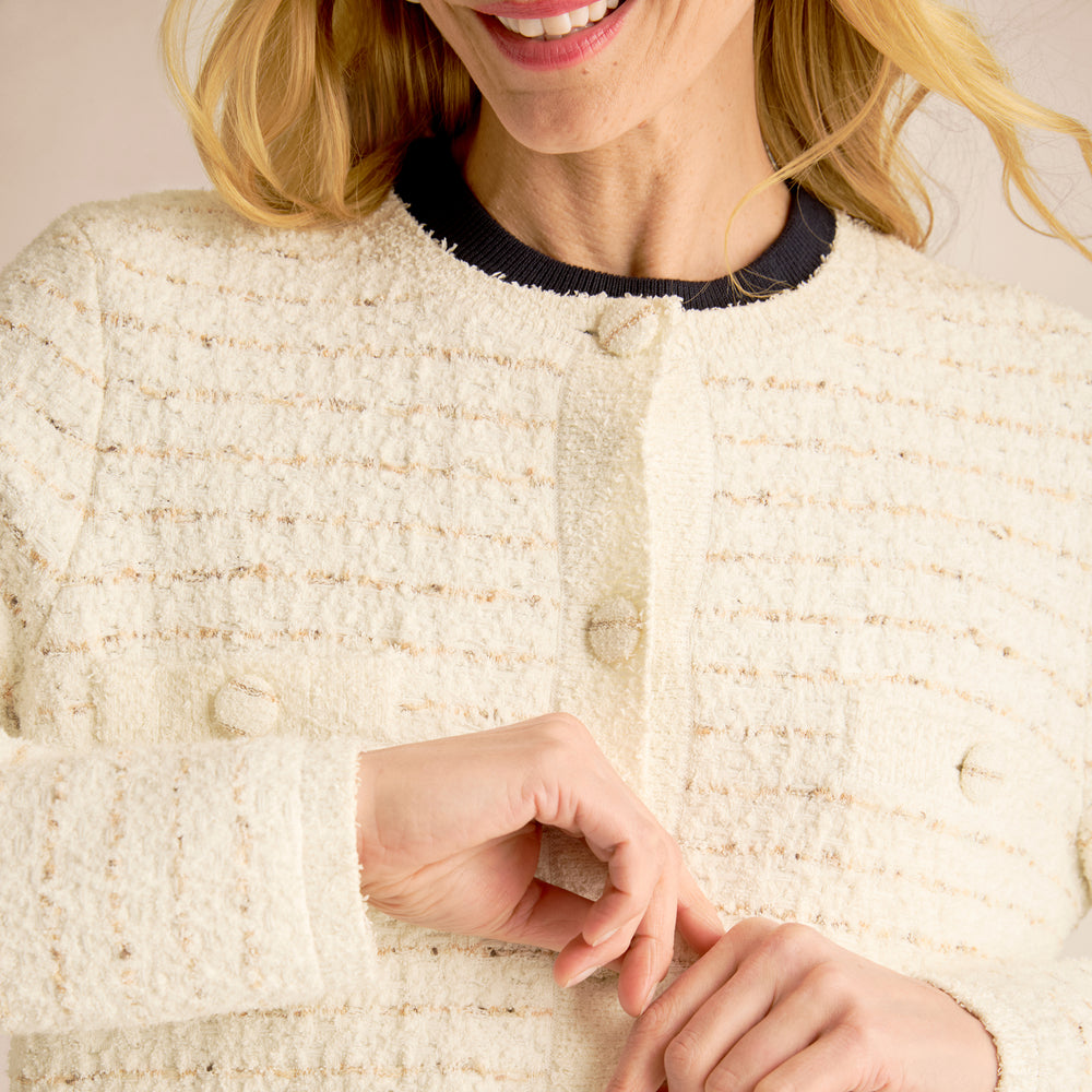 Close-up of a person wearing a textured beige jacket with a blurred background