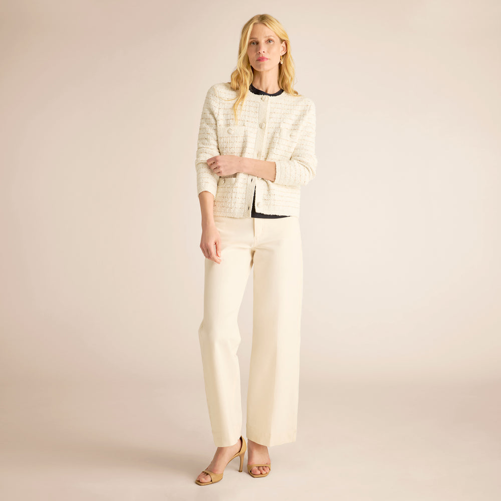 Woman wearing a cream-colored outfit against a plain background