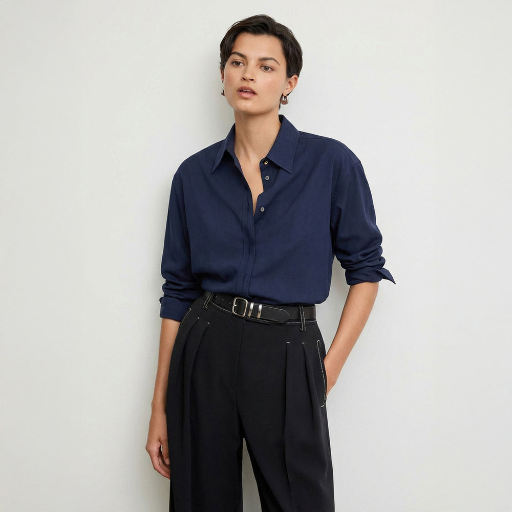 Person wearing a navy blue shirt and black pants on a light gray background