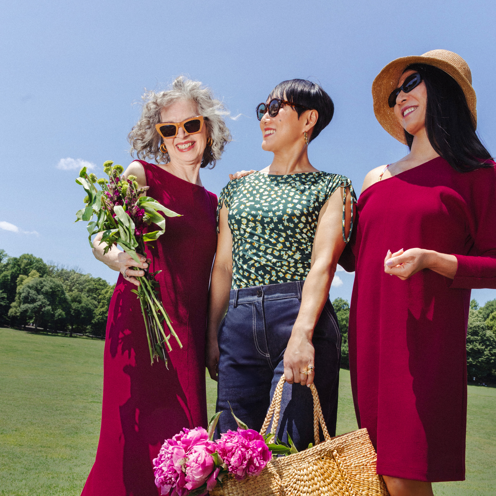 Three women standing outdoors on a sunny day, wearing sunglasses and hats.