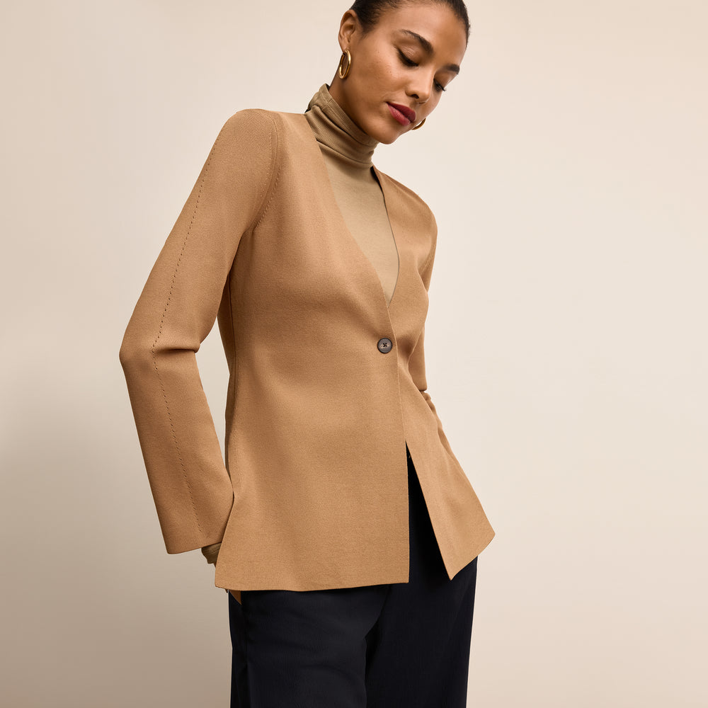 Woman wearing a beige blazer over a black top on a beige background