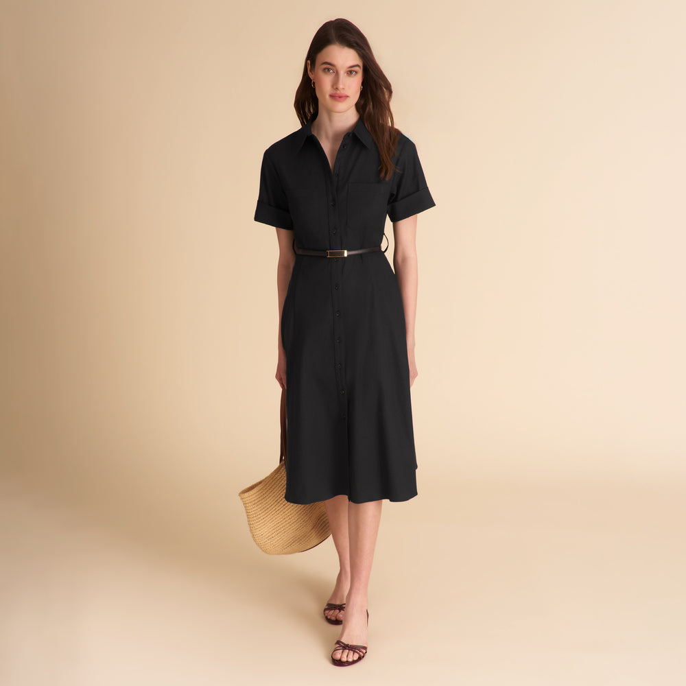 Woman wearing a black dress with a belt against a beige background