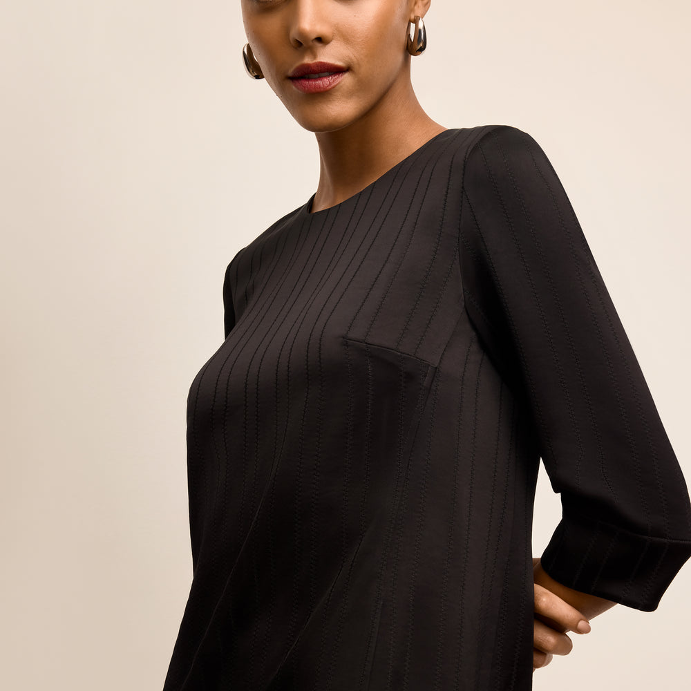 Woman wearing a black dress with long sleeves on a beige background