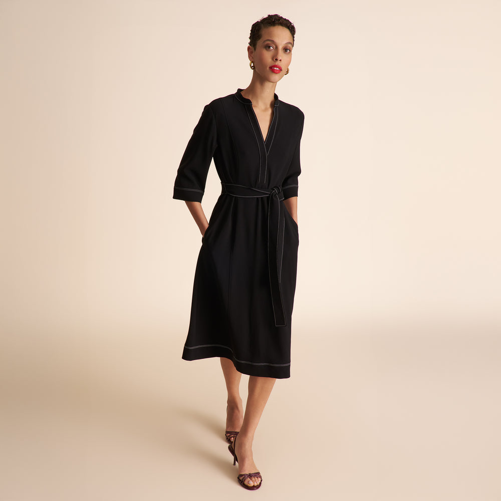 Woman wearing a black dress against a beige background