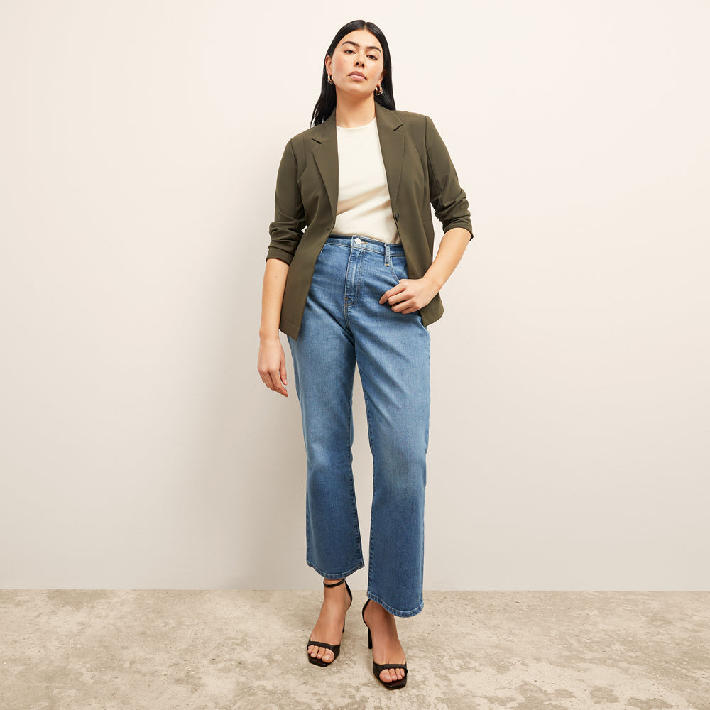 front image of a woman sitting wearing the frame le jane ankle jeans in deepwater