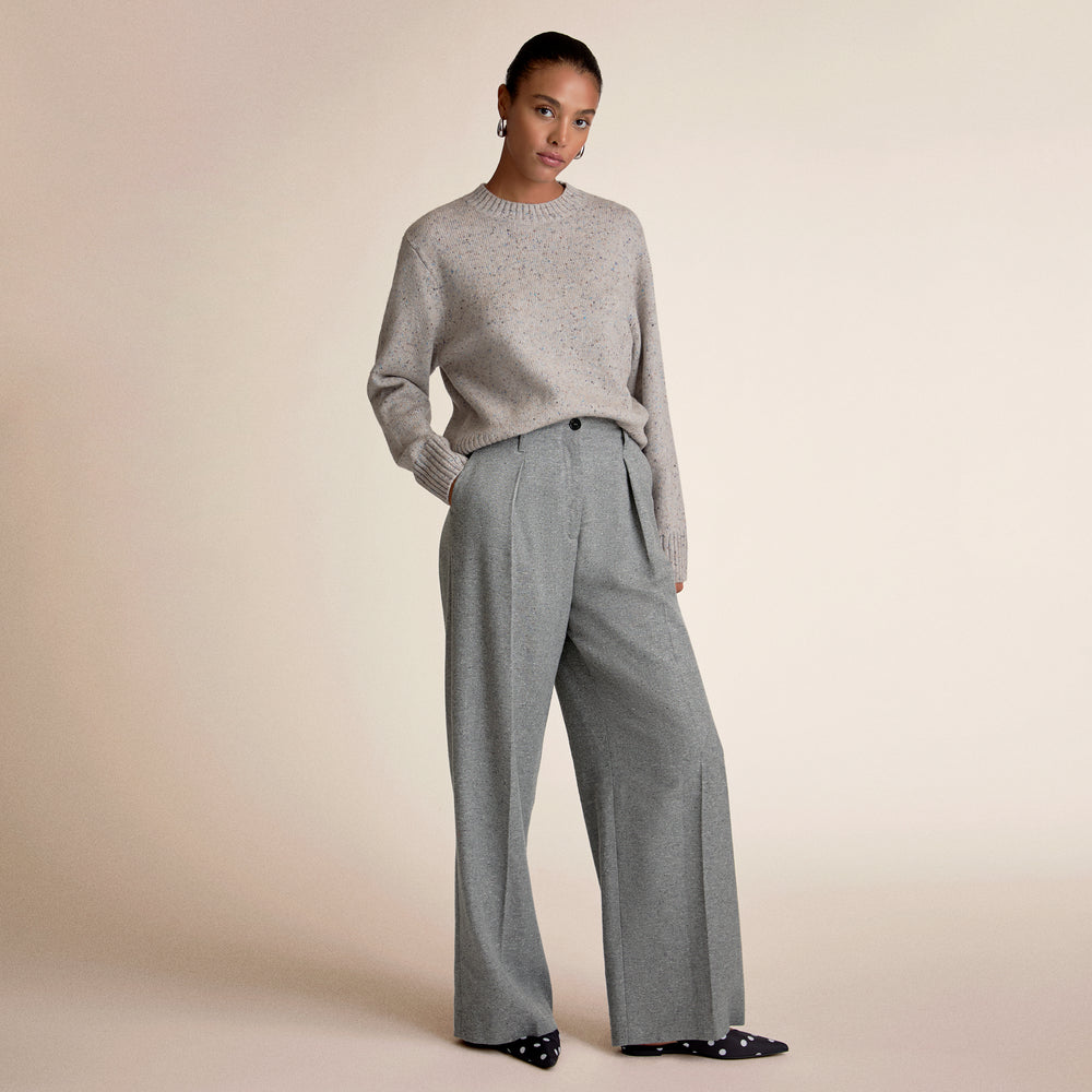 Woman wearing a gray sweater and matching wide-leg pants on a beige background