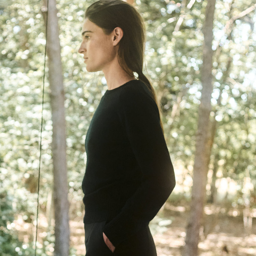 Woman in a black sweater standing in a forest