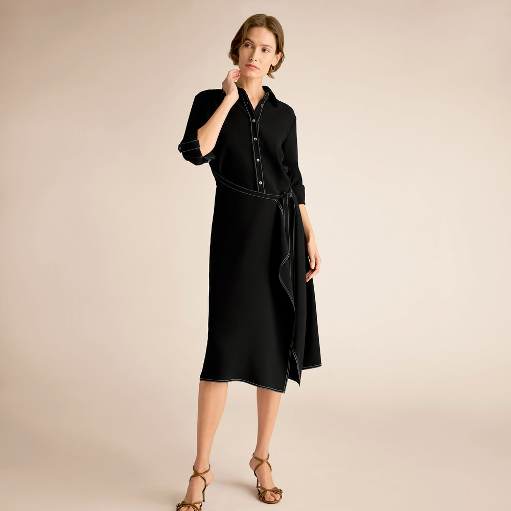 Woman wearing a black dress with a belt on a beige background