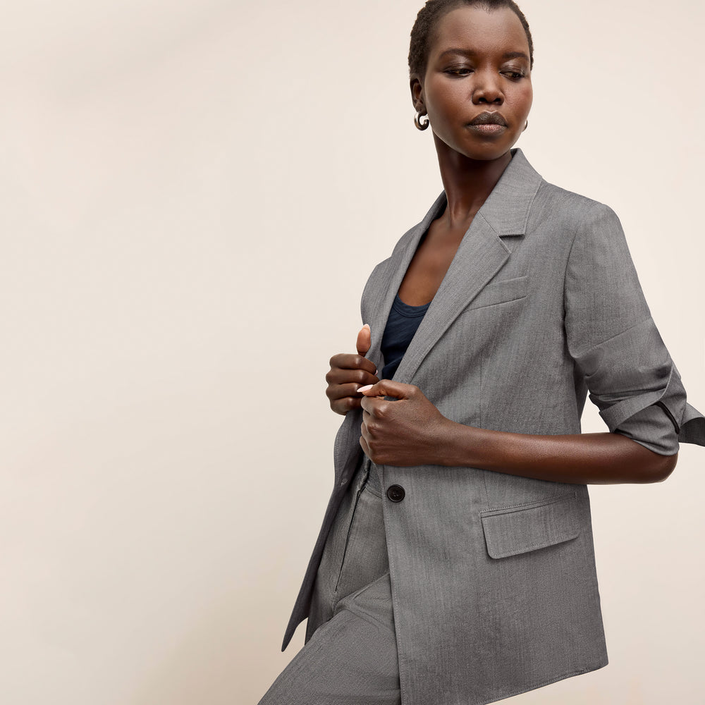 Woman wearing a gray blazer against a beige background