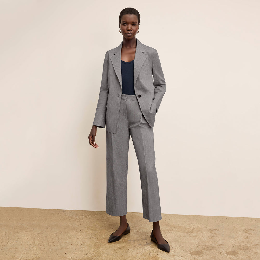 Woman wearing a gray suit with a black top on a beige background