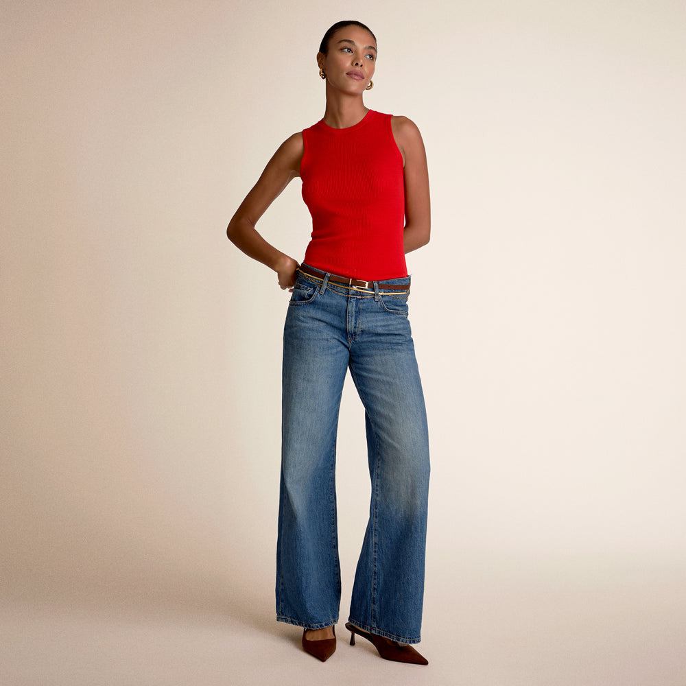 A woman wearing a red top and blue jeans