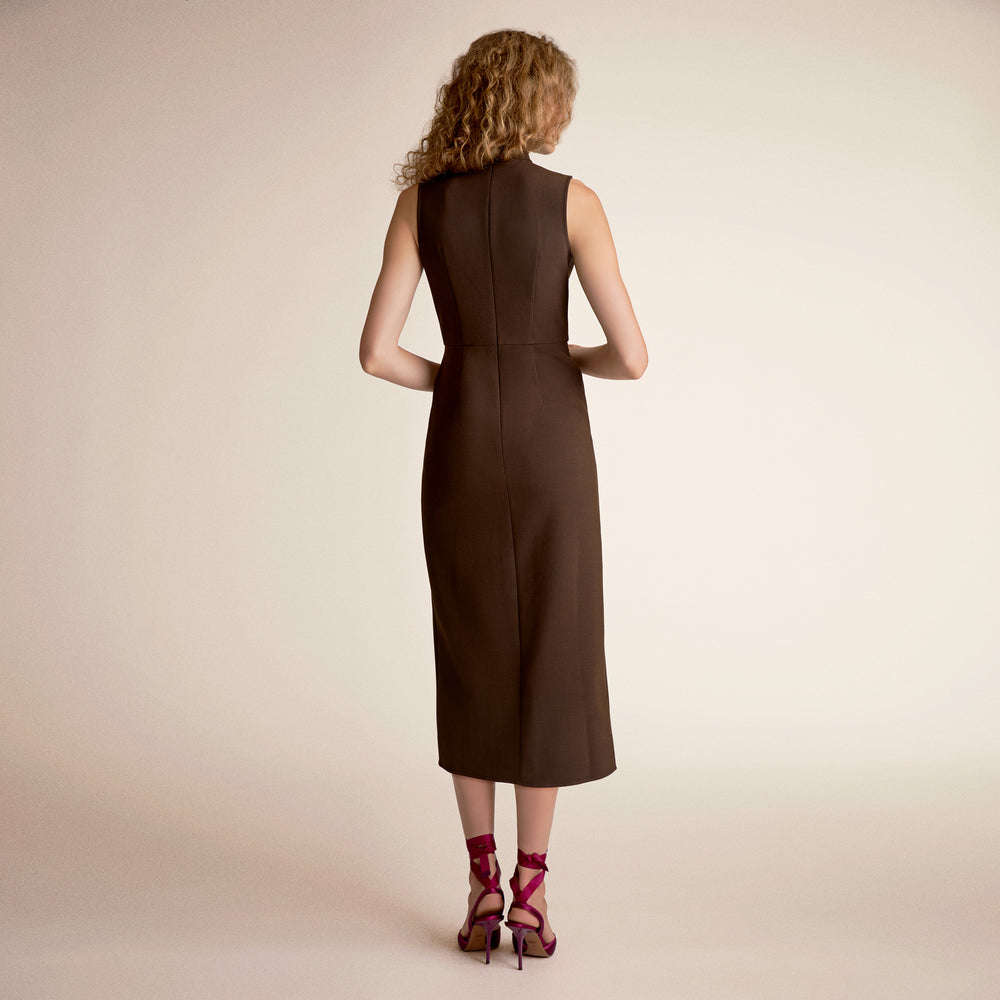 Woman wearing a brown dress from behind on a beige background