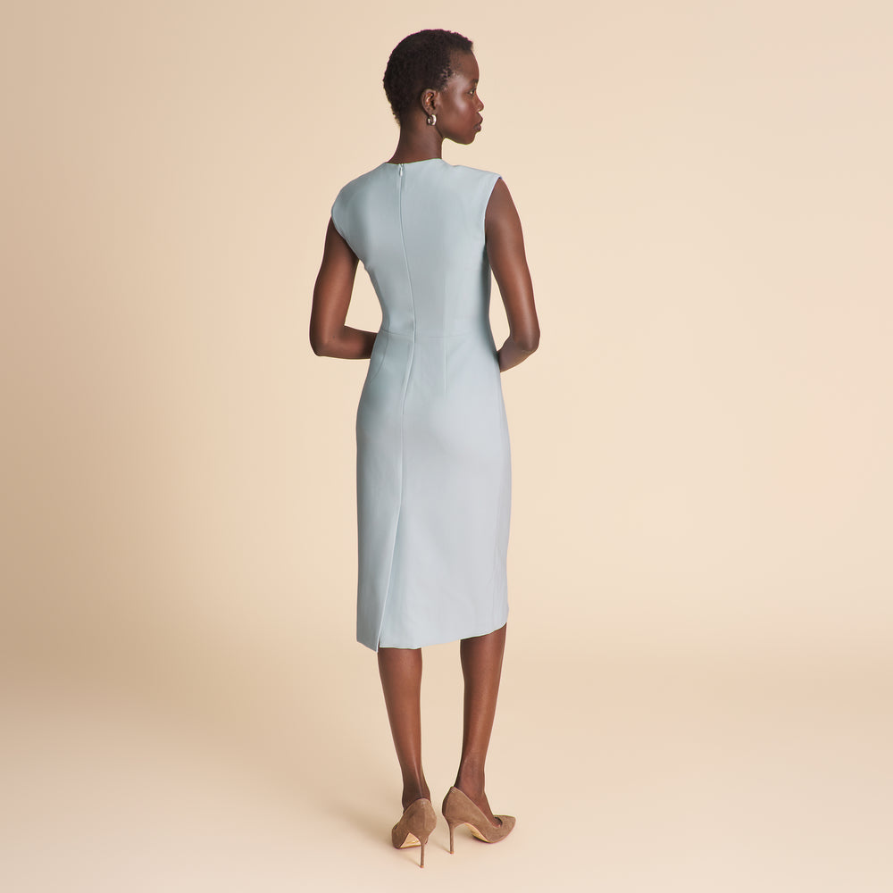 Woman wearing a light blue v neck dress on a beige background