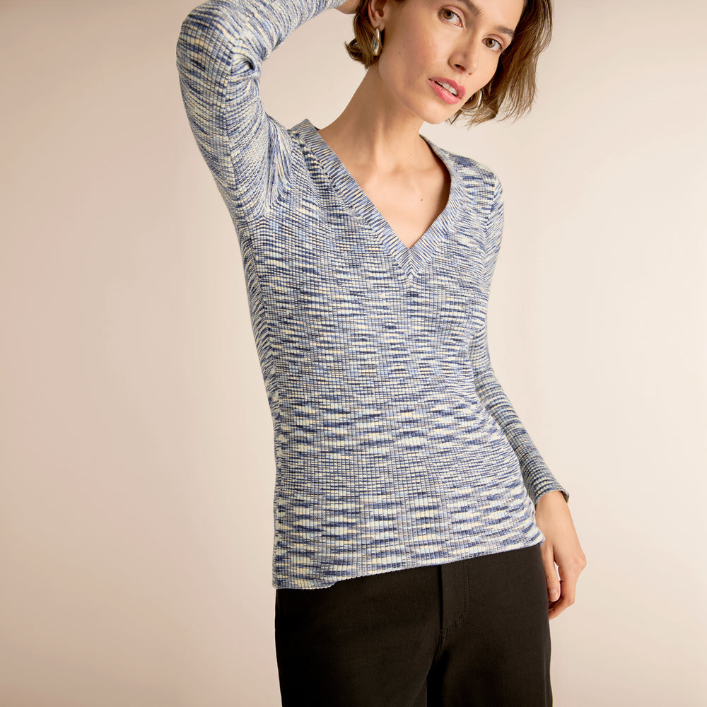 Woman wearing a blue and white patterned long-sleeve top against a beige background