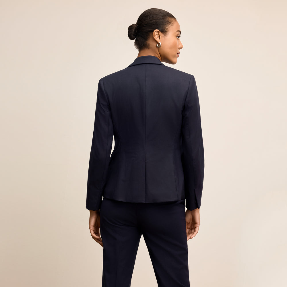 Woman wearing a navy blue suit on a beige background