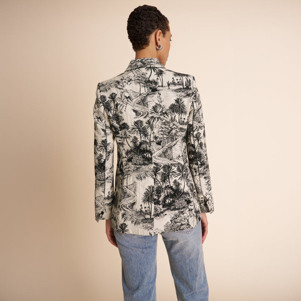Person wearing a patterned jacket and jeans on a beige background