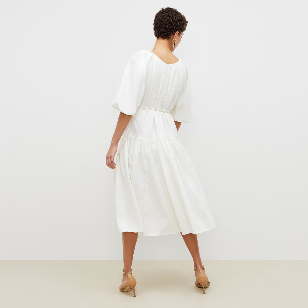 Back image of a woman standing wearing the medina dress in textured voile in ivory