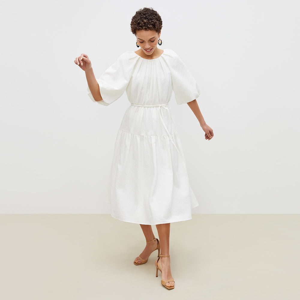 Front image of a woman standing wearing the medina dress in textured voile in ivory