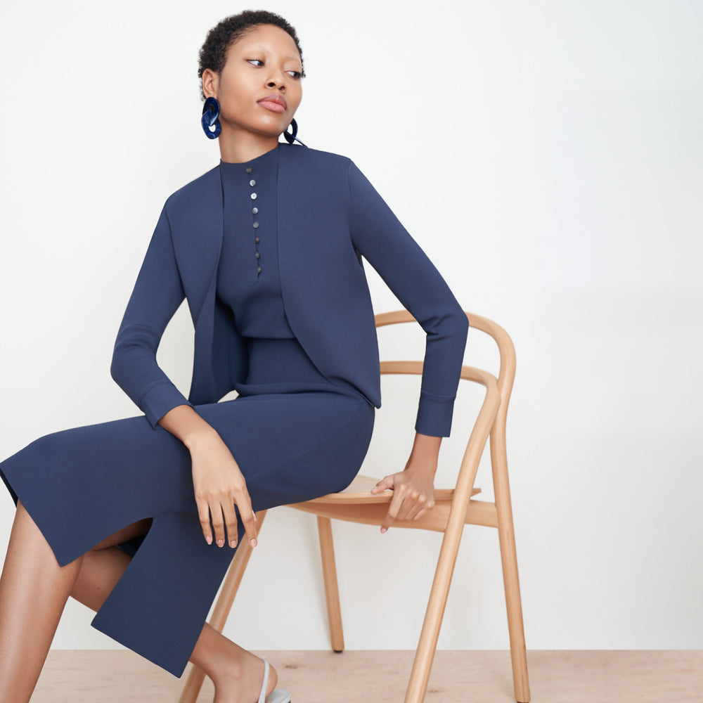 Side image of a woman sitting wearing the Harlem skirt in jardigan knit in Baltic Blue
