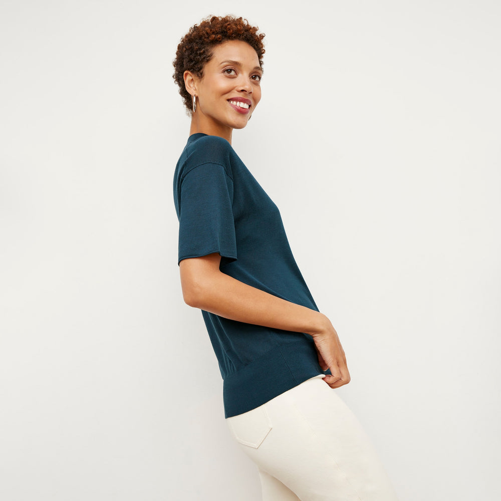 Side image of a woman standing wearing the mia top in silk jersey in deep sea