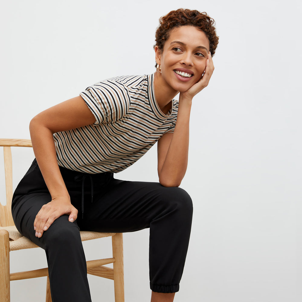Front image of a woman wearing the Leslie T-Shirt - Thin Striped Pima Cotton in Tan / Black