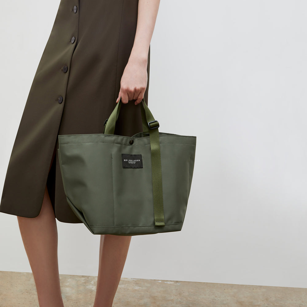 Front image of a woman wearing the Bags in Progress x MM Small Carry All Tote in Khaki Green