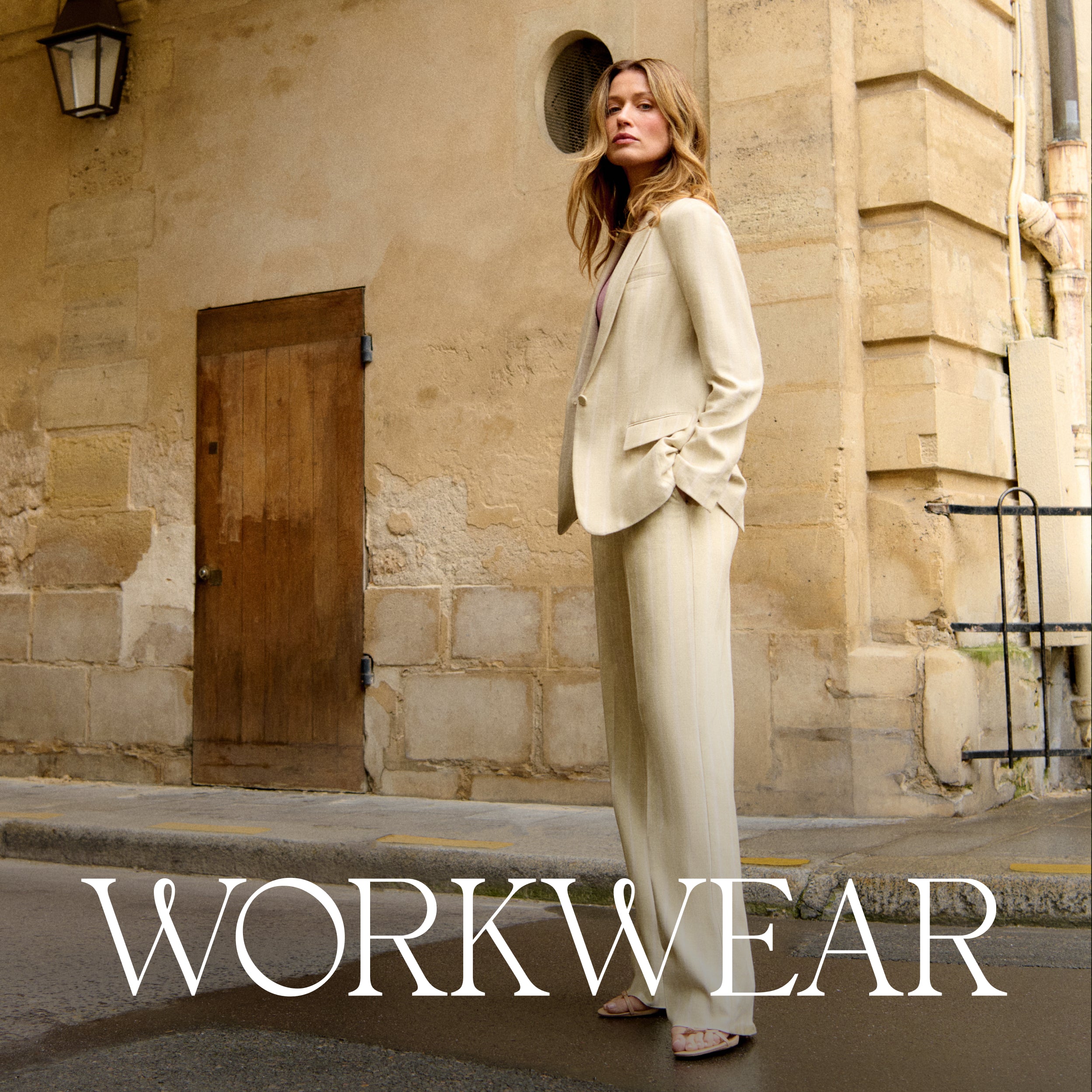 Woman in a beige suit standing on a street with 'WORKWEAR' text overlay.