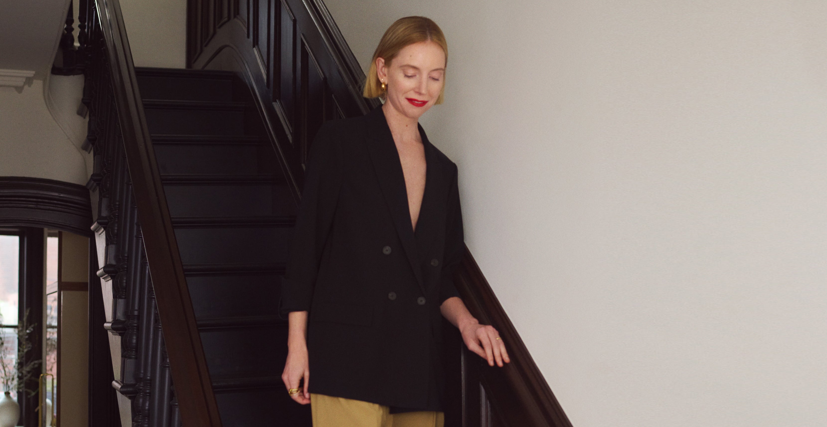Erin Jennie Pollard walking down the stairs in the O'Hara Blazer in Black and the Bia Pant in Macaroon