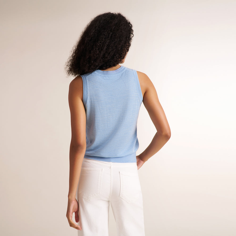 Woman wearing alight blue short sleeve sweater tank and wide leg white jeans