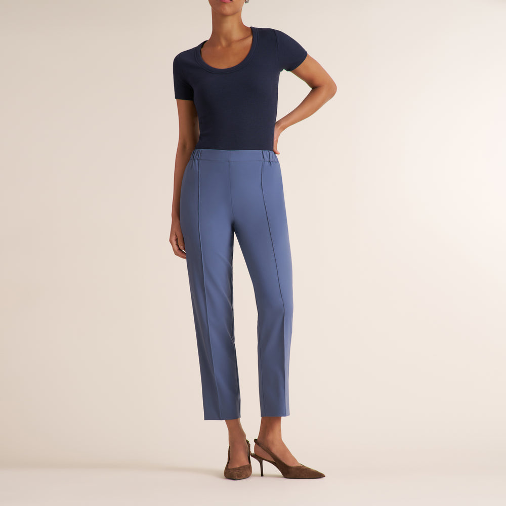 Woman wearing a scoop neck short sleeve navy t-shirt with light blue travel trousers