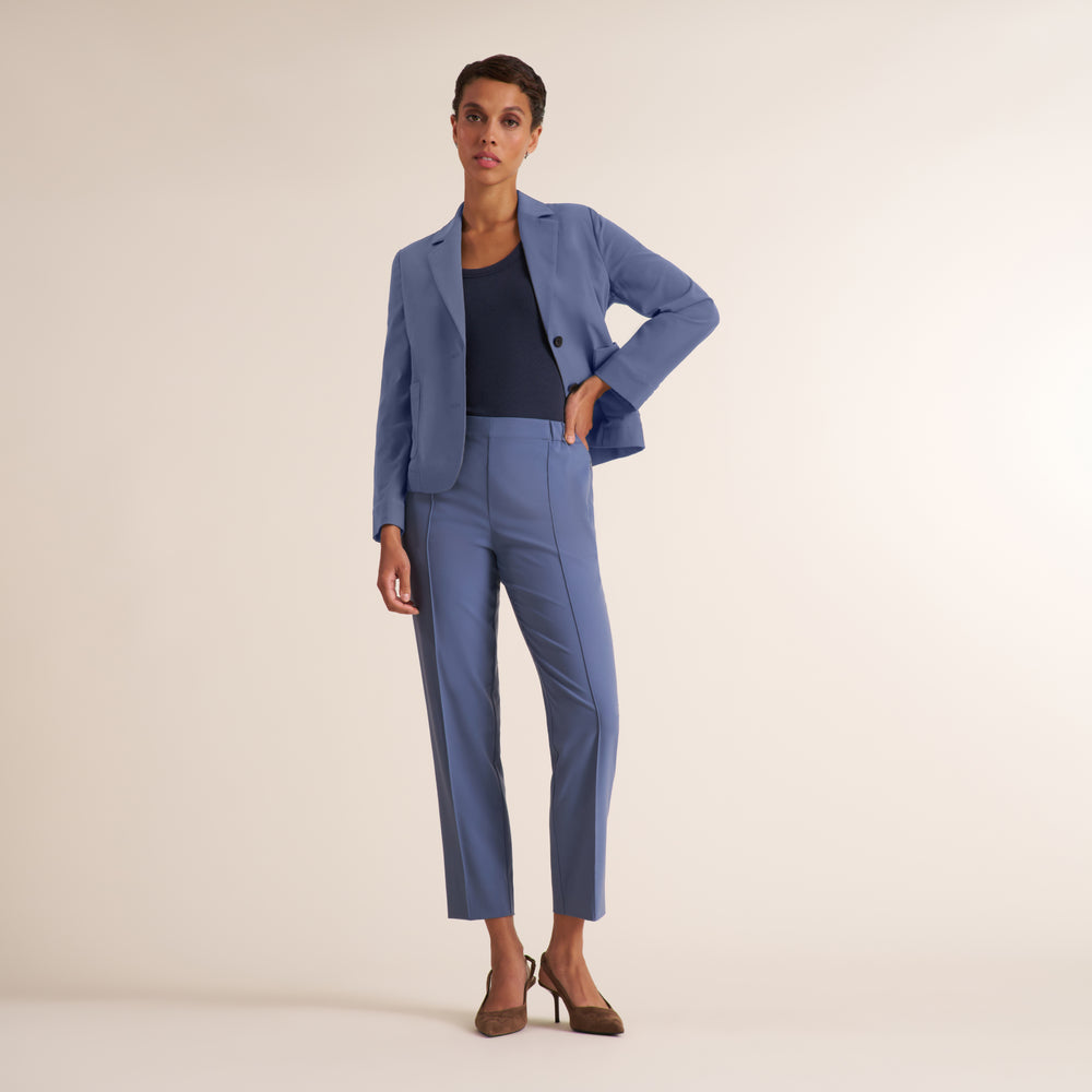 Woman wearing a scoop neck short sleeve navy t-shirt with light blue travel trousers and matching blazer