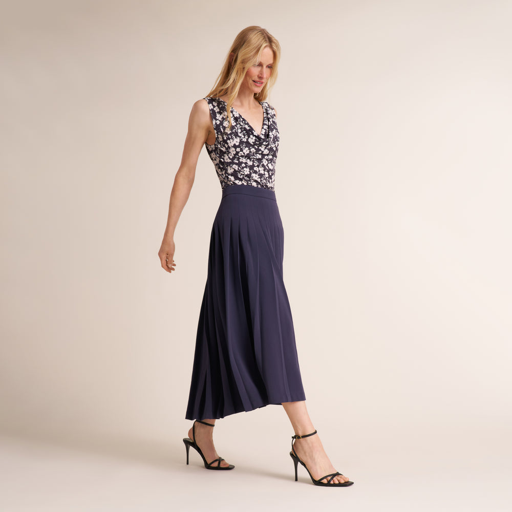 Woman wearing a pleated oxford colored midi skirt with printed top