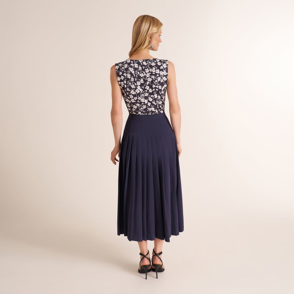 Woman wearing a pleated oxford colored midi skirt with printed top
