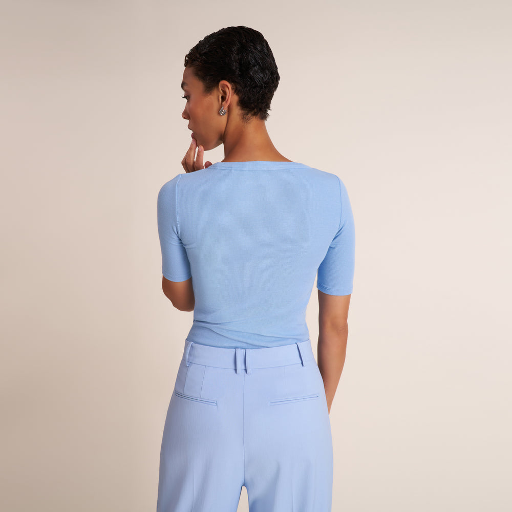 Woman wearing a crew neck, short sleeve t-shirt with light blue trouser pants