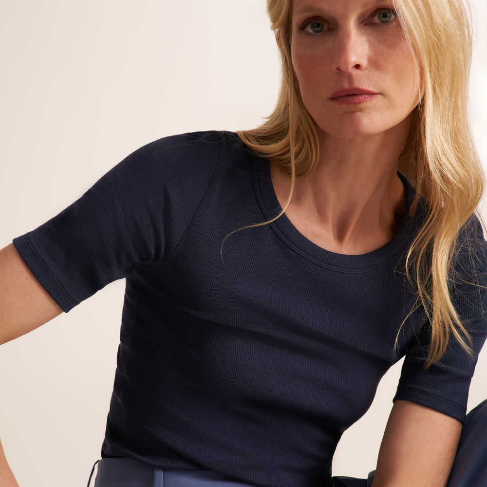 Woman wearing a navy crew neck, short sleeve t-shirt with blue trouser pants