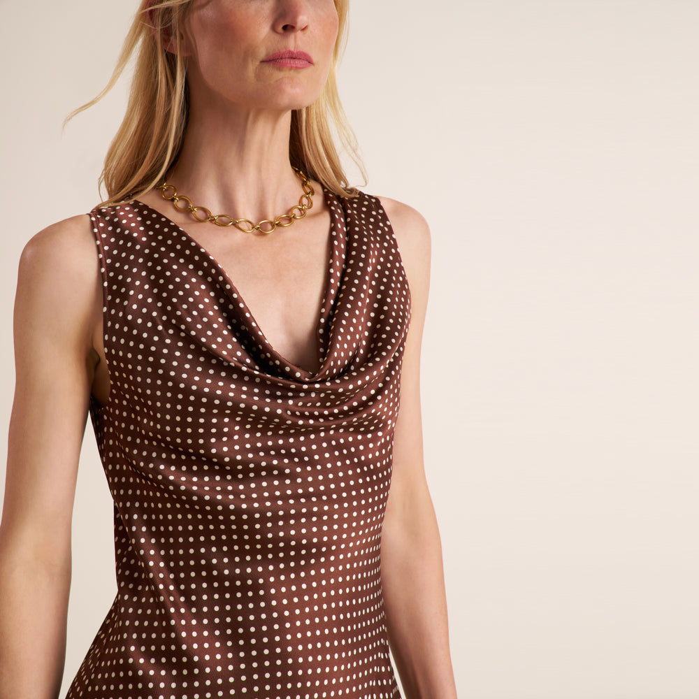 Woman wearing a sleevless maxi dress in a brown and white dot print