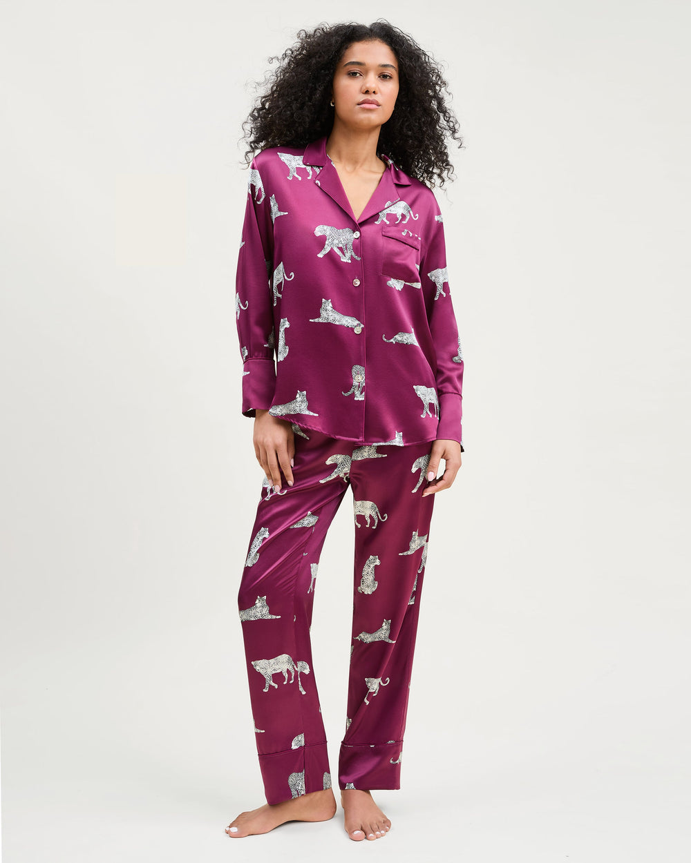 Woman wearing a purple pajama set with animal prints on a white background